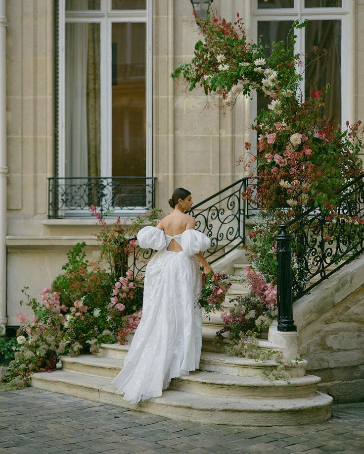 Bride descending floral-lined stone staircase at a Parisian hôtel particulier